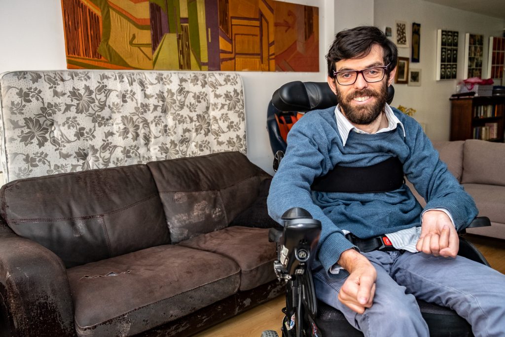 Jacob, a white man in his thirties, seated in a wheelchair in his living room