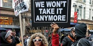 A Black Lives Matter protestor holds up a sigh sayinh, 'We won't take it anymore'