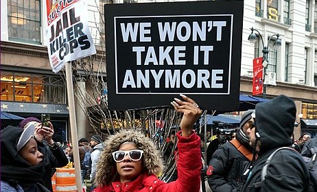 A Black Lives Matter protestor holds up a sign saying, 'We won't take it anymore'