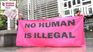 People on a protest holding a banner which reads 'No Human is Illegal'