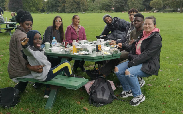 A group of 8 people from round the world sit at a picnic table